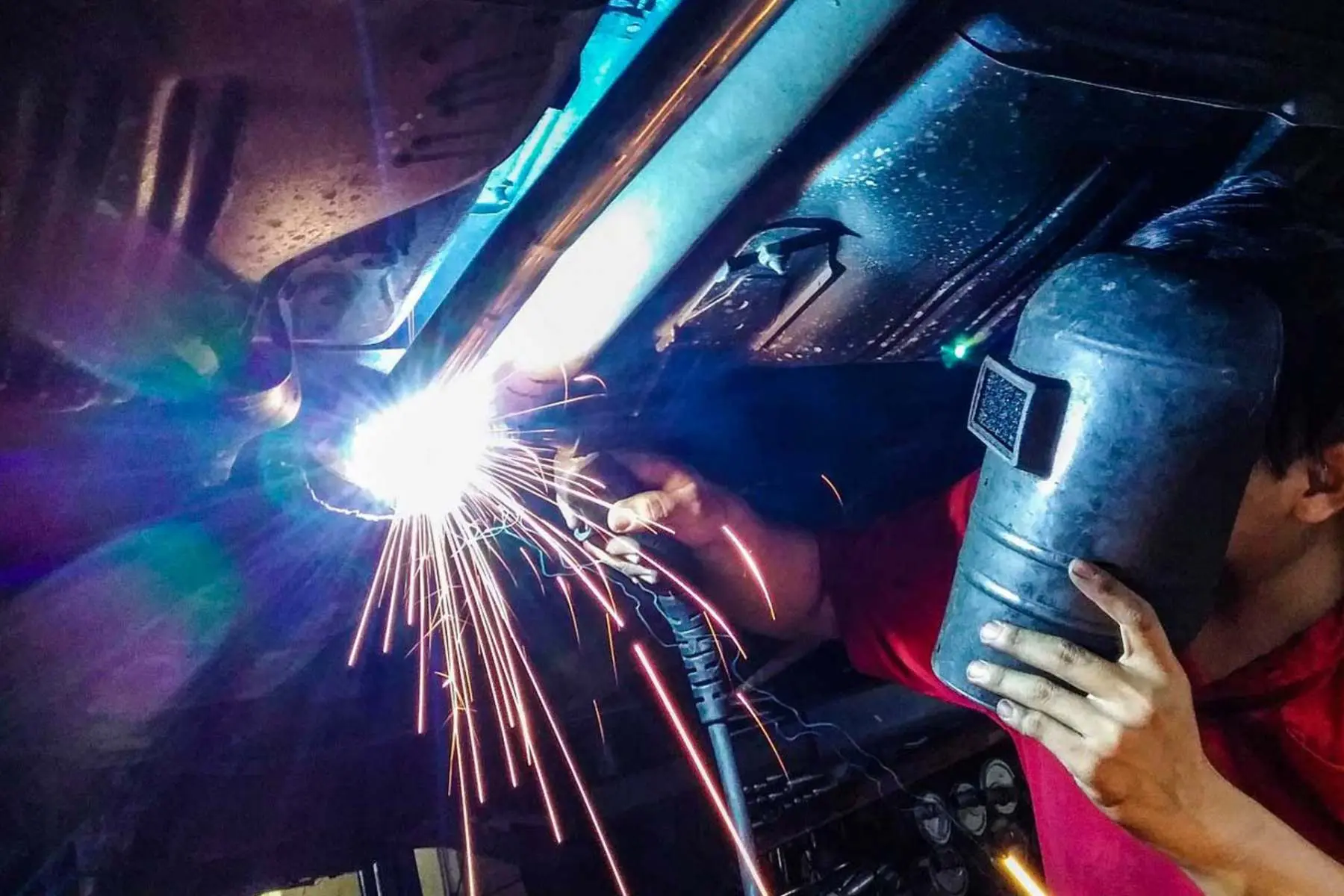 Welder repairing the underside of a car body at C.A.M.S. garage Chippenham