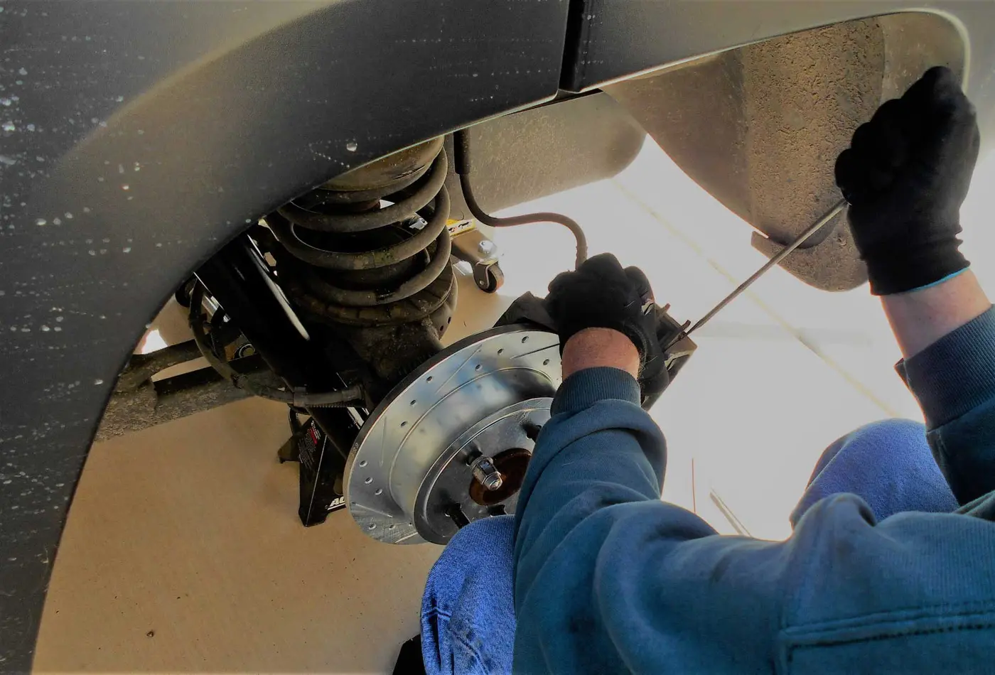 Mechanic replacing brake pads and rotors on a car at C.A.M.S. garage Chippenham