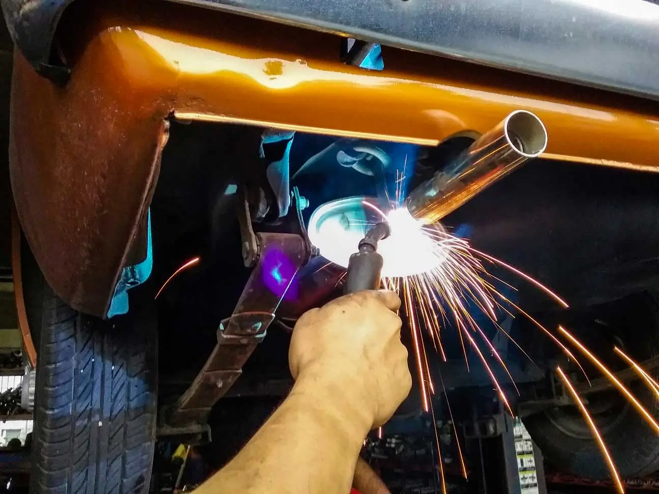 Welder repairing a car exhaust muffler at C.A.M.S. garage Chippenham