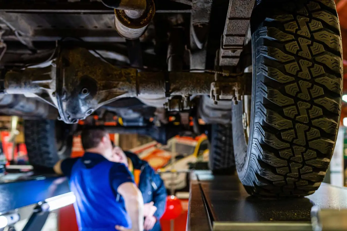 Mechanic checking the underside of a lifted car for corrosion at C.A.M.S. Chippenham
